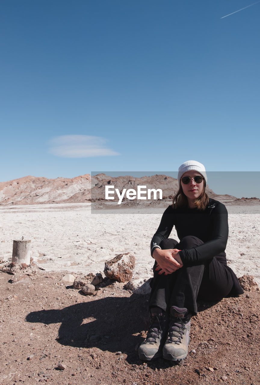 Full length of woman sitting on land against sky