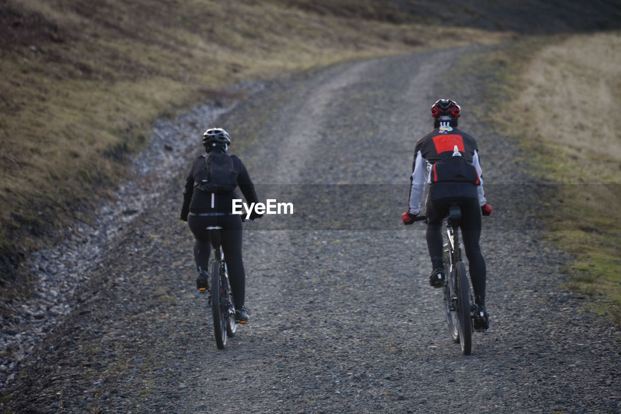 Rear view of men riding bicycle on street