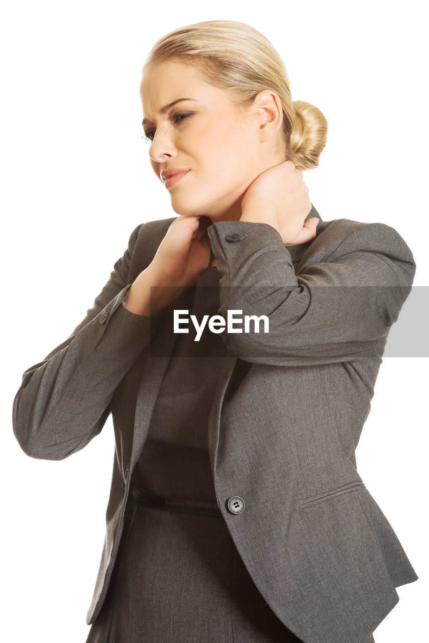 Businesswoman with neckache standing against white background