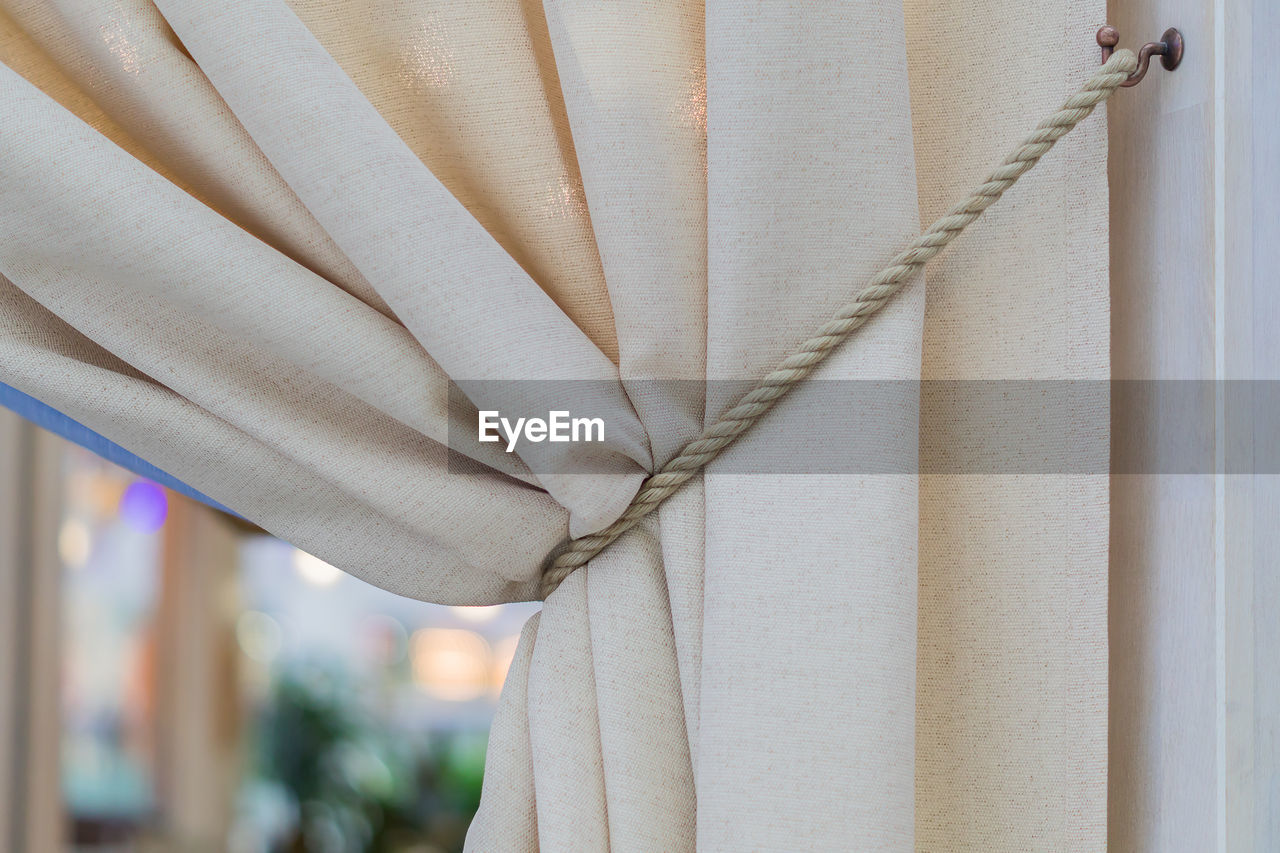 Interior design element - beige curtains tied with cord, italian style