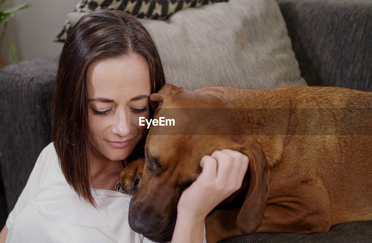 portrait of young woman with dog at home