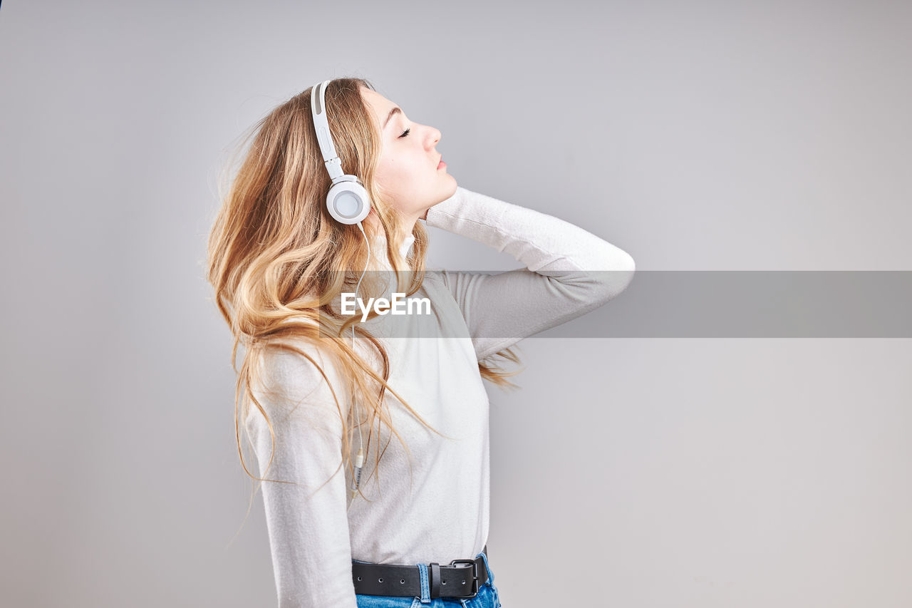 Woman listening music against gray background