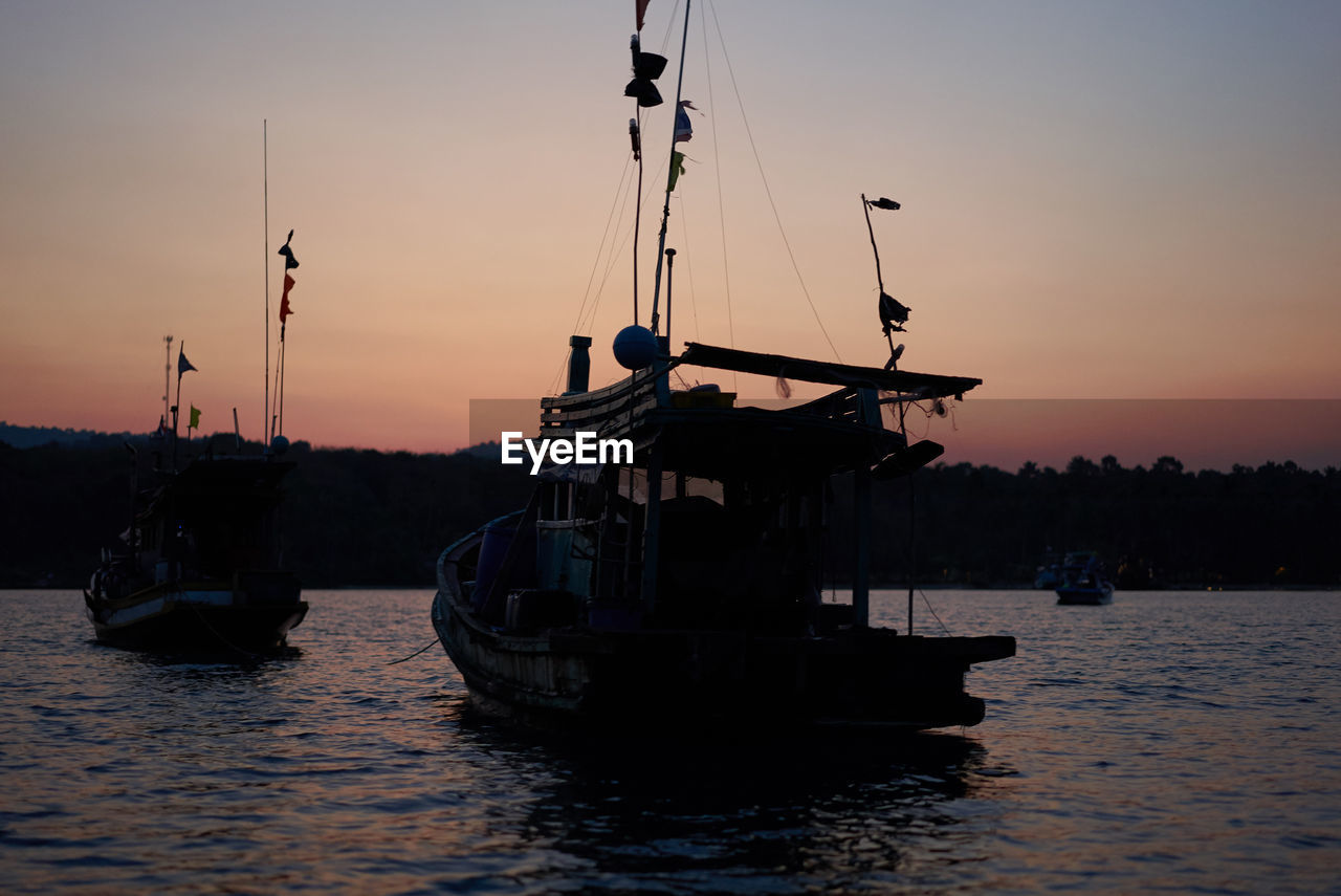 Silhouette ship in sea against sky during sunset