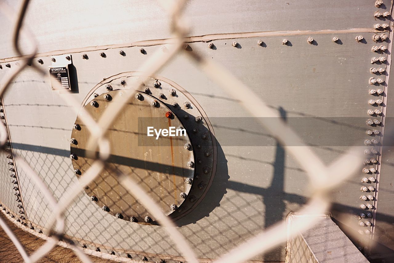 Metal container in factory seen through chainlink fence