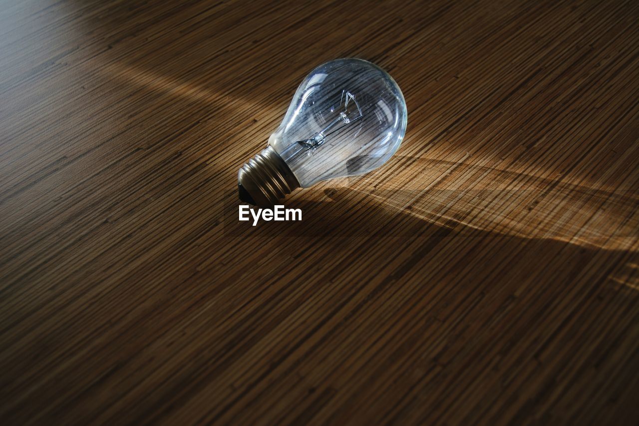 Close-up of light bulb on wooden table