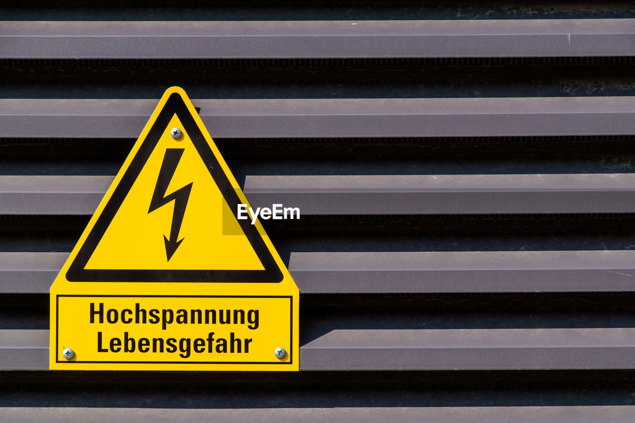 Close-up of high voltage sign on metallic wall