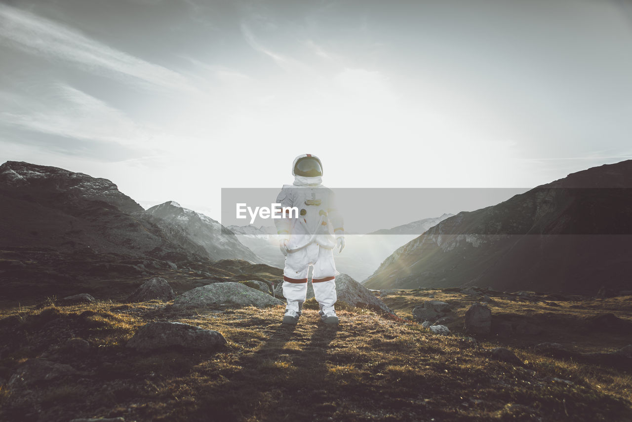 Astronaut standing on land against mountain