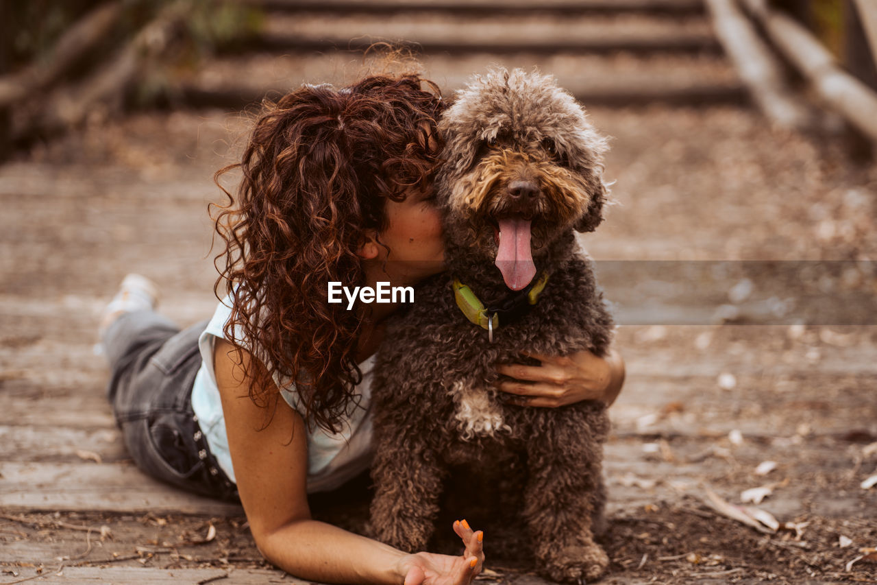 Woman embracing dog lying on road