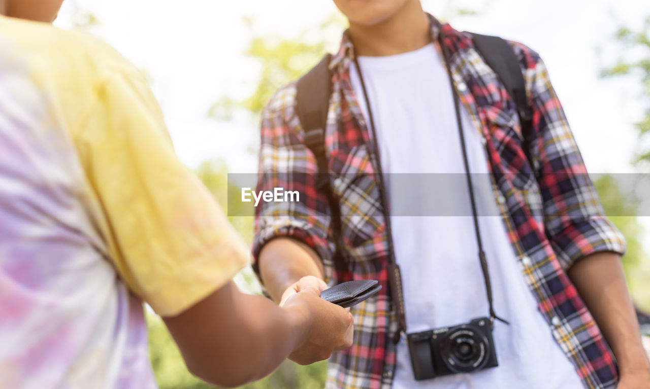 Midsection of boy giving wallet to man