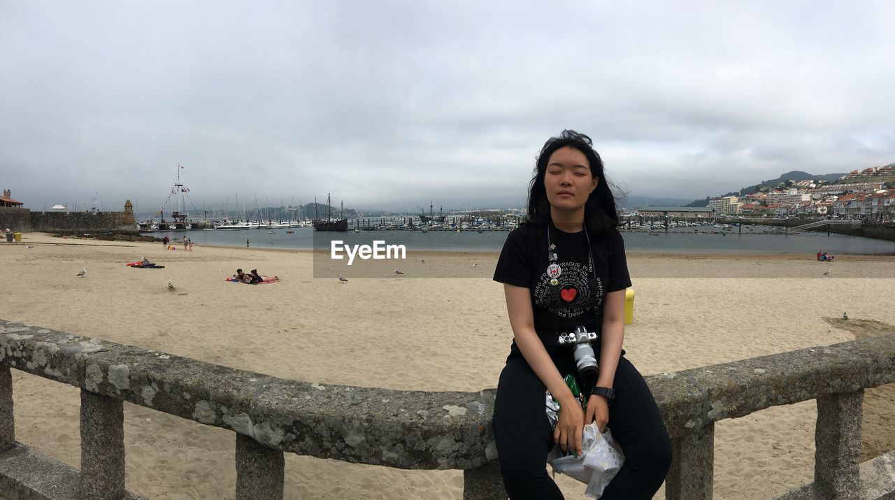 PORTRAIT OF WOMAN STANDING AGAINST SEA