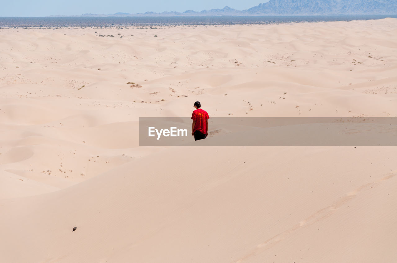 Teenage boy on desert against sky