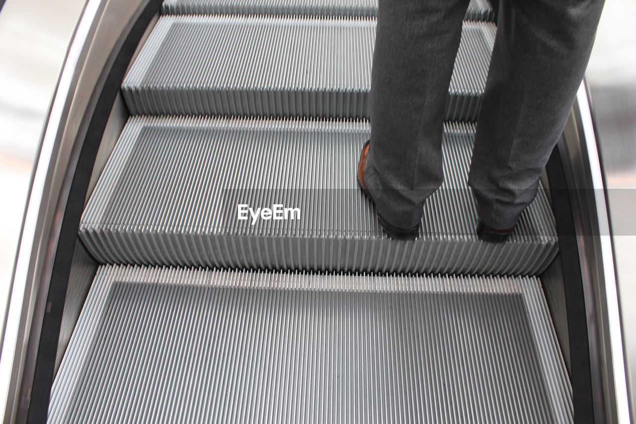 LOW SECTION OF MAN ON ESCALATOR IN OFFICE