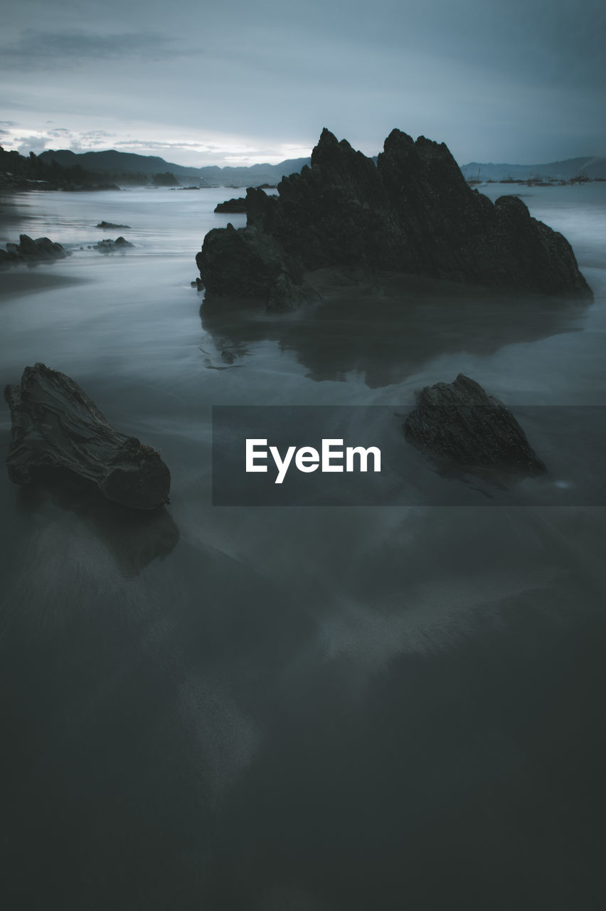 Rock formation in sea against sky