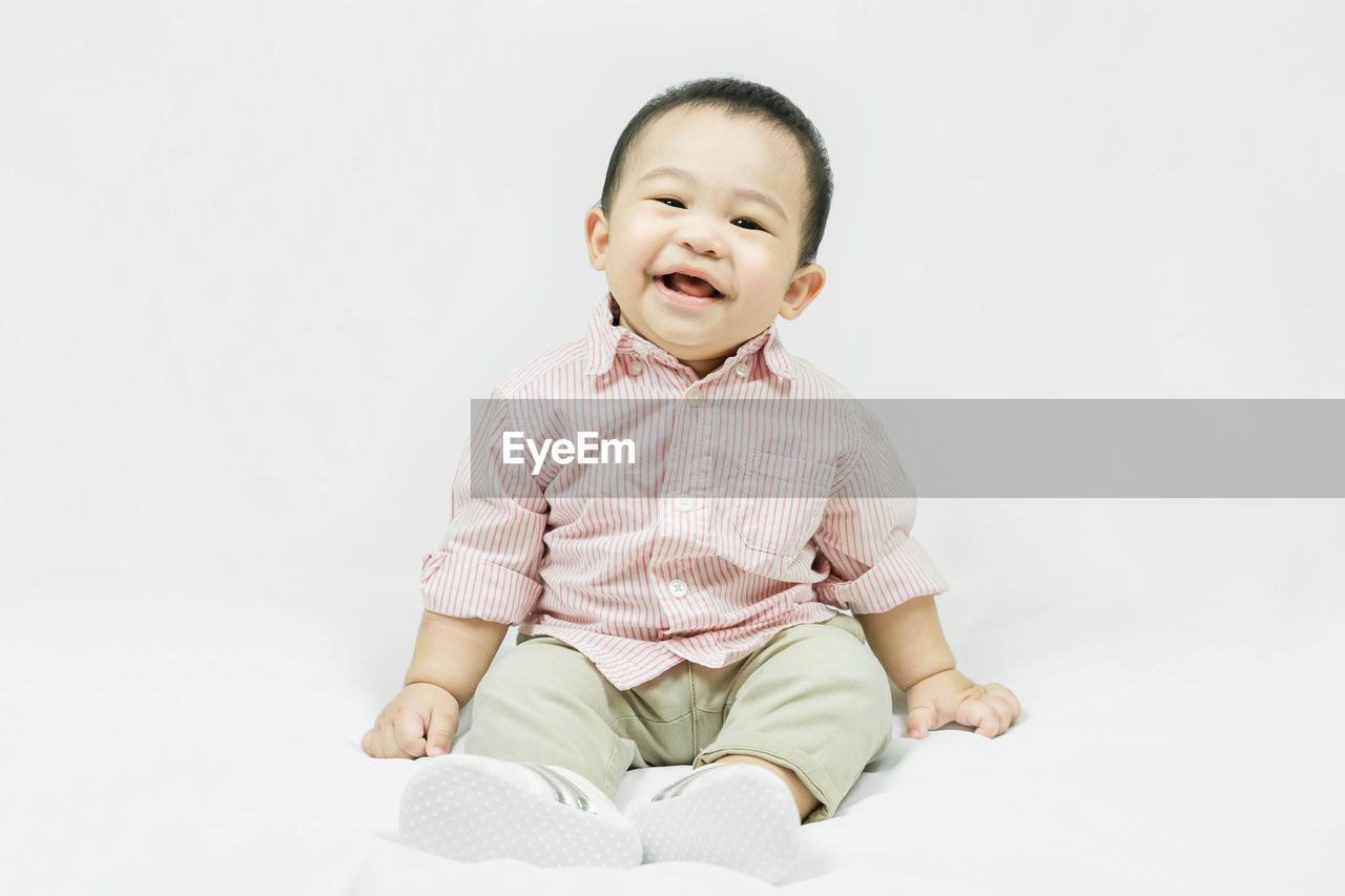 one person, childhood, child, sitting, baby, studio shot, indoors, white background, toddler, full length, cute, person, happiness, portrait, smiling, front view, emotion, innocence, baby clothing, laughing, copy space, portrait photography, cheerful, clothing, joy, fun, cut out, positive emotion, men, looking at camera, casual clothing, looking, facial expression, human face, mouth open, lifestyles