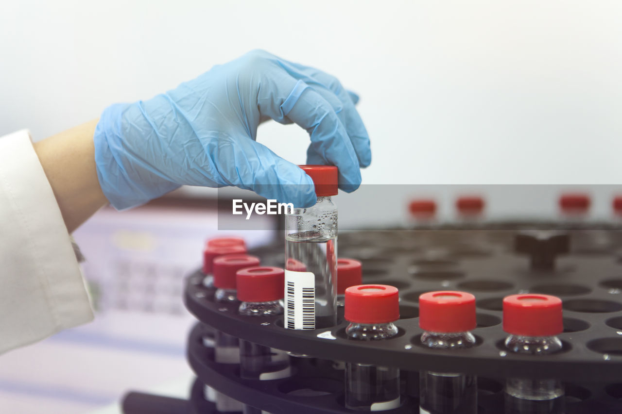 Close-up of human hand holding bottle over rack in laboratory