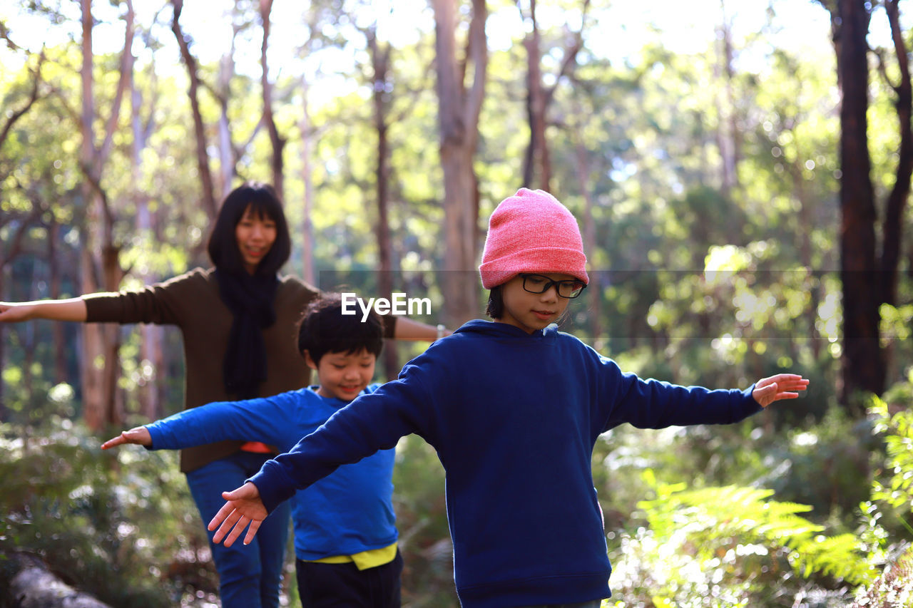 Family with arms outstretched walking in forest