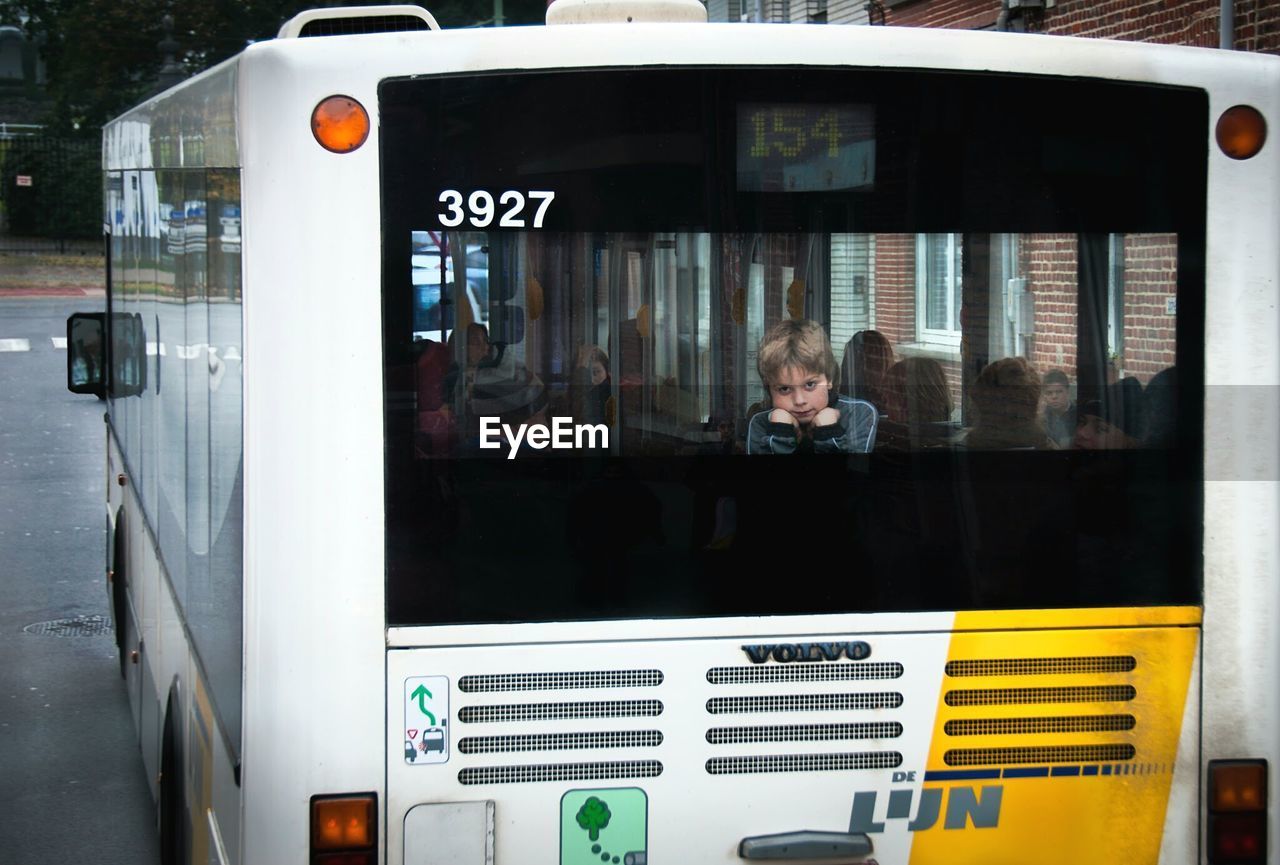 Portrait of boy seen through bus glass windshield