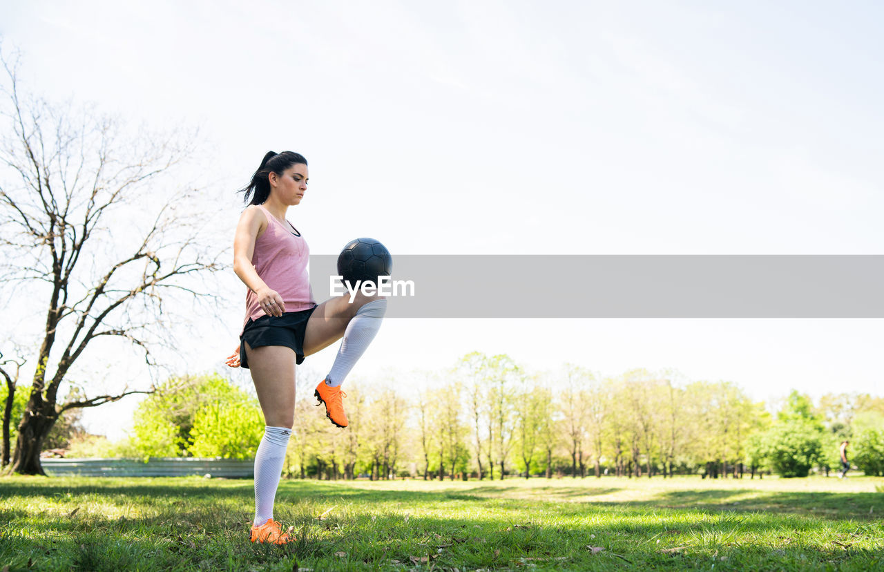 Full length of woman playing on field against sky