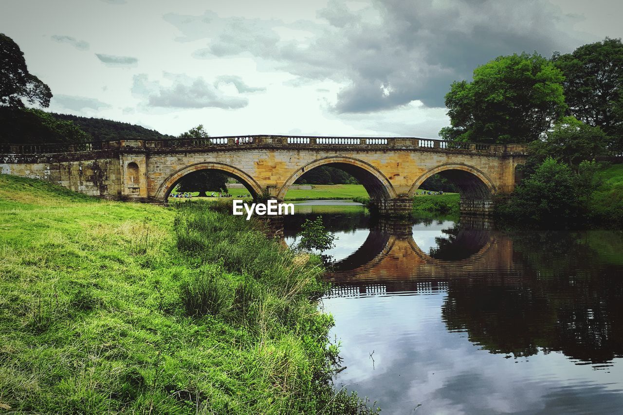 Arch bridge over river against sky