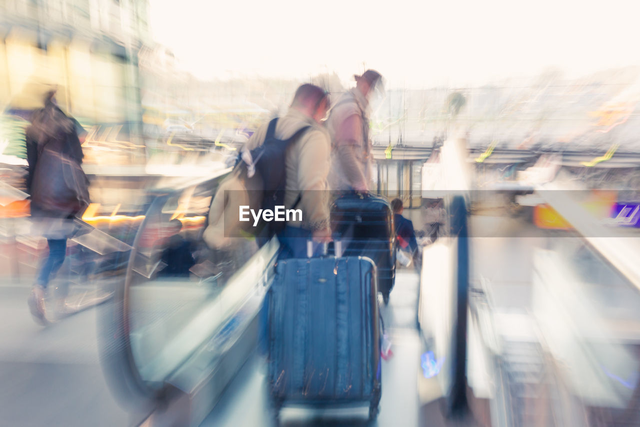 Blurred motion of people with luggage on escalator