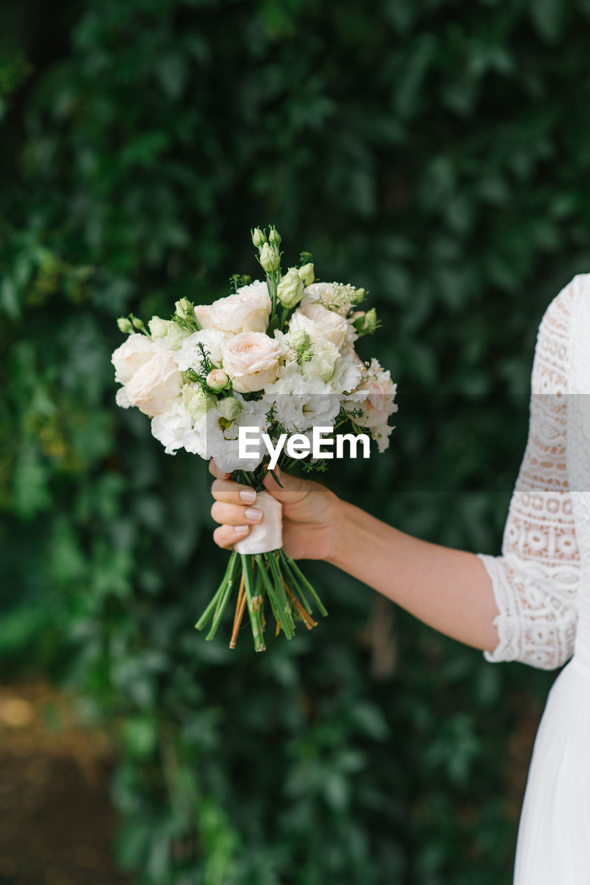 The bride holds a beautiful wedding bouquet of white flowers in her hands