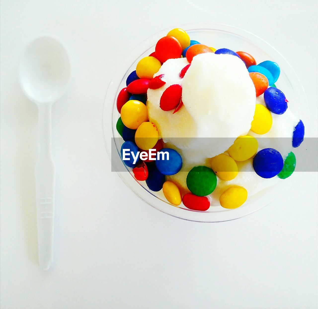 High angle view of multi colored candies in ice cream served by spoon on table