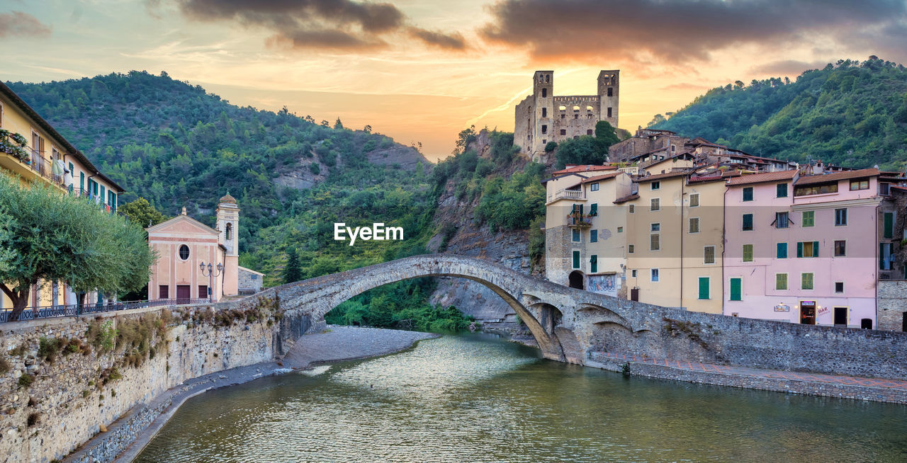 BRIDGE OVER RIVER BY BUILDINGS AGAINST SKY