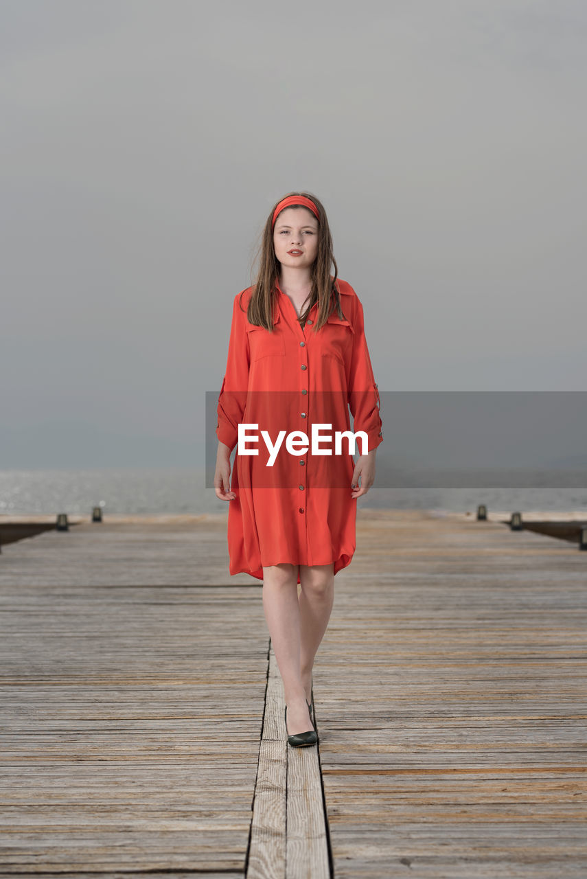 Portrait of woman standing on pier against sky during sunset