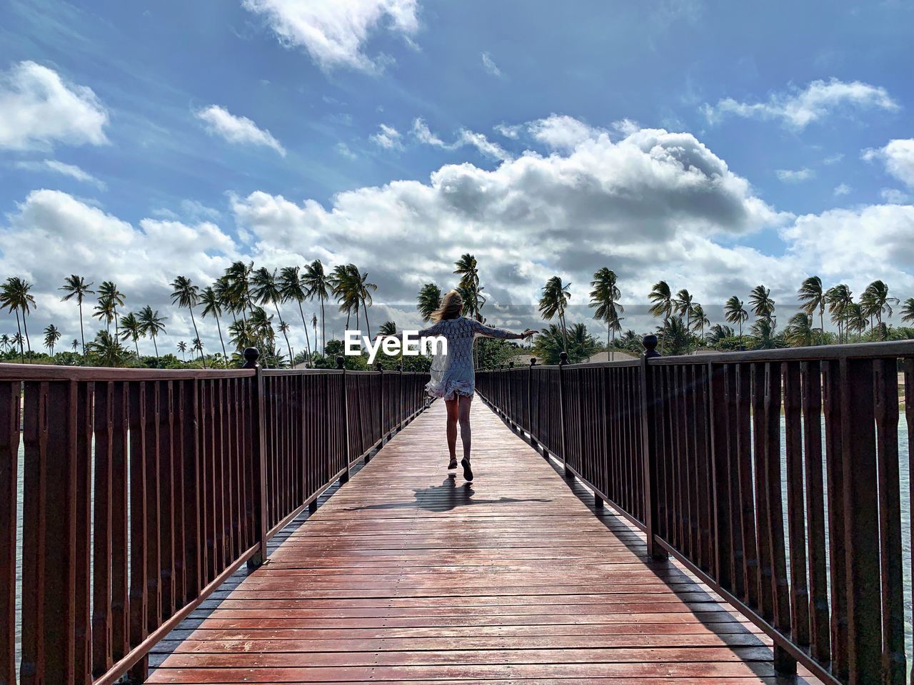 Rear view of woman walking on footbridge