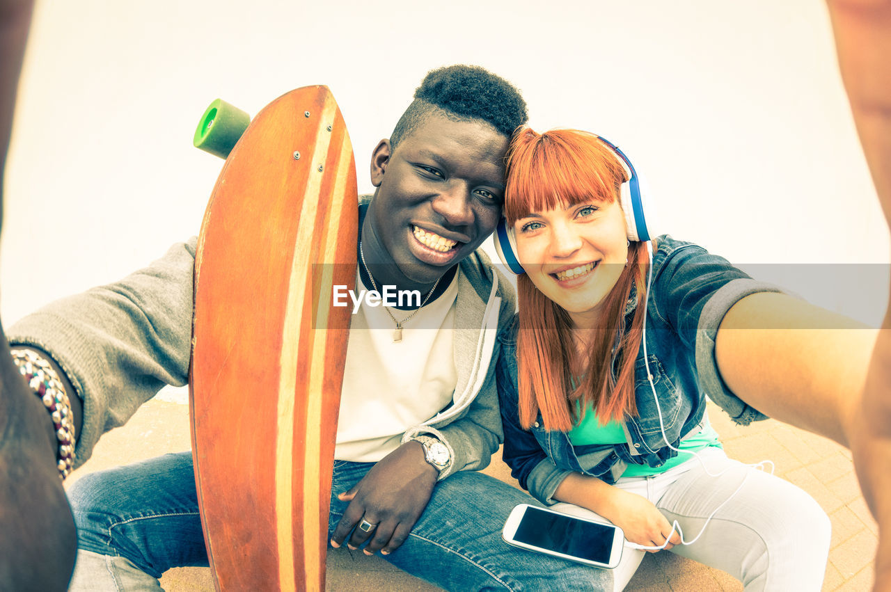 Portrait of cheerful young couple sitting outdoors