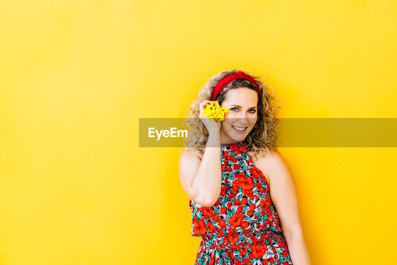 Portrait of smiling beautiful girl on yellow background