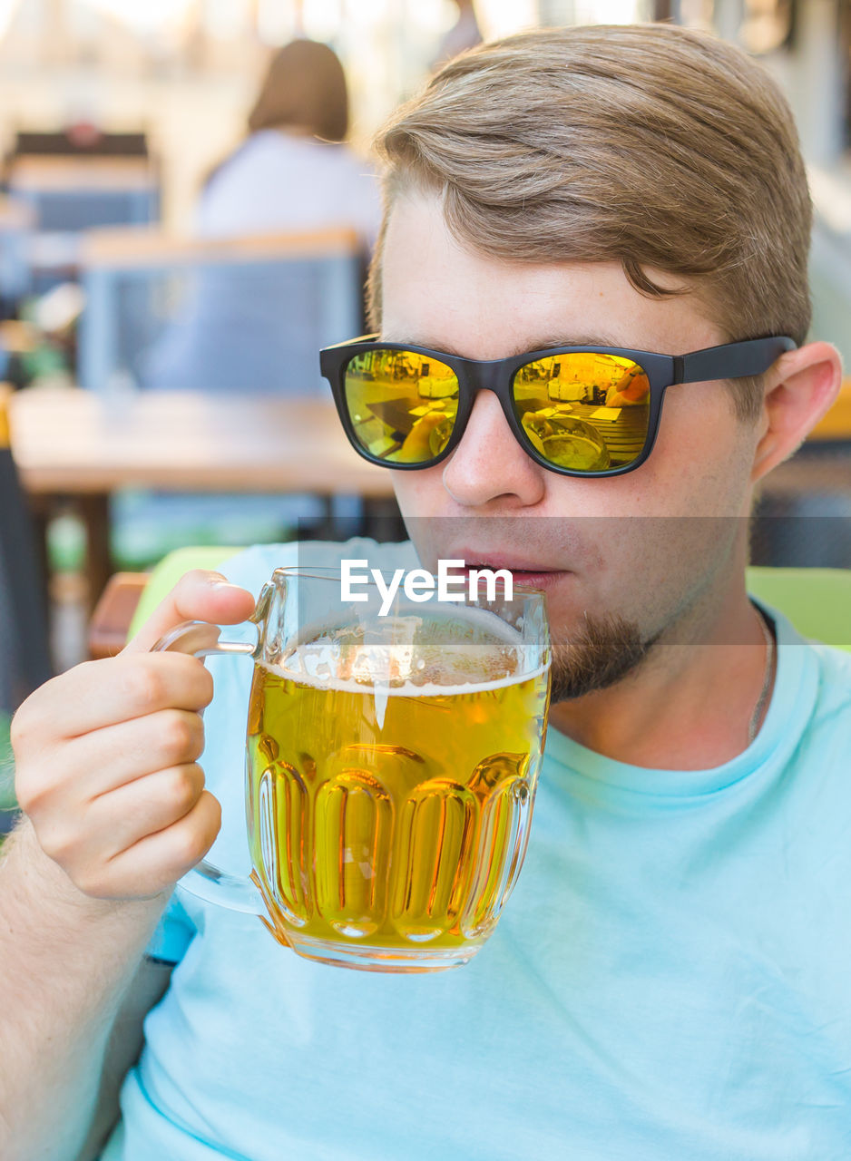 PORTRAIT OF YOUNG MAN DRINKING GLASS IN SUNGLASSES