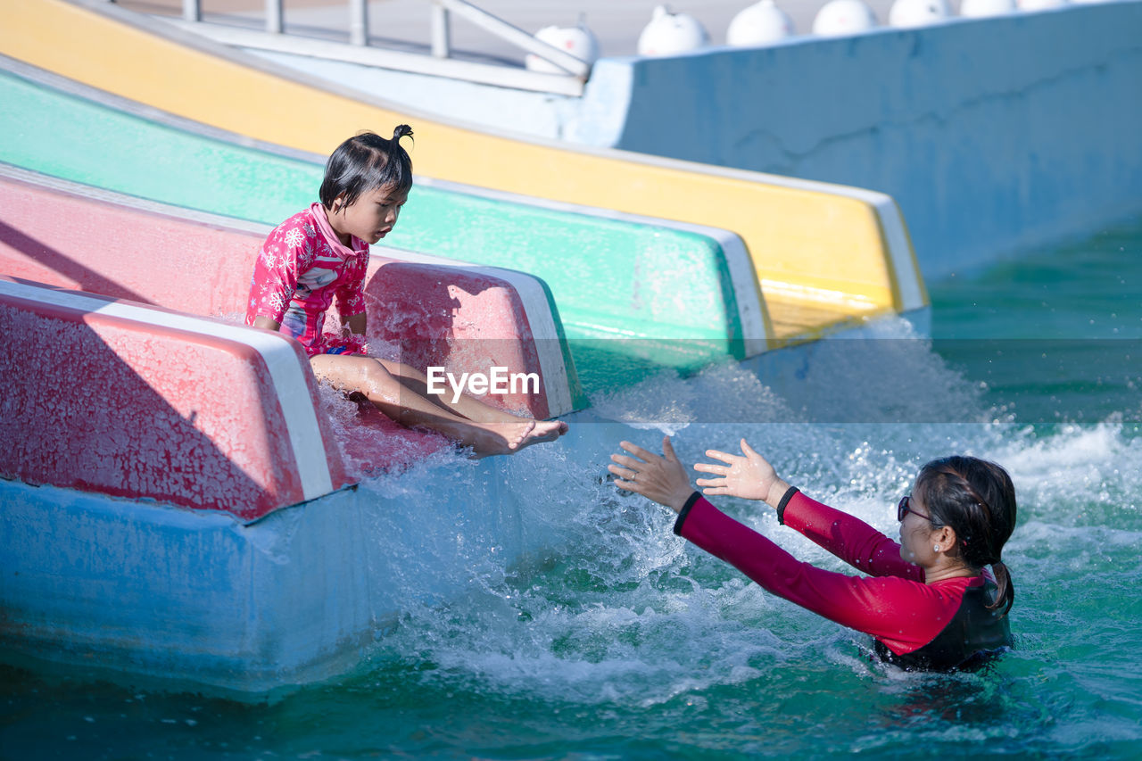 Mother and daughter playing on water slide