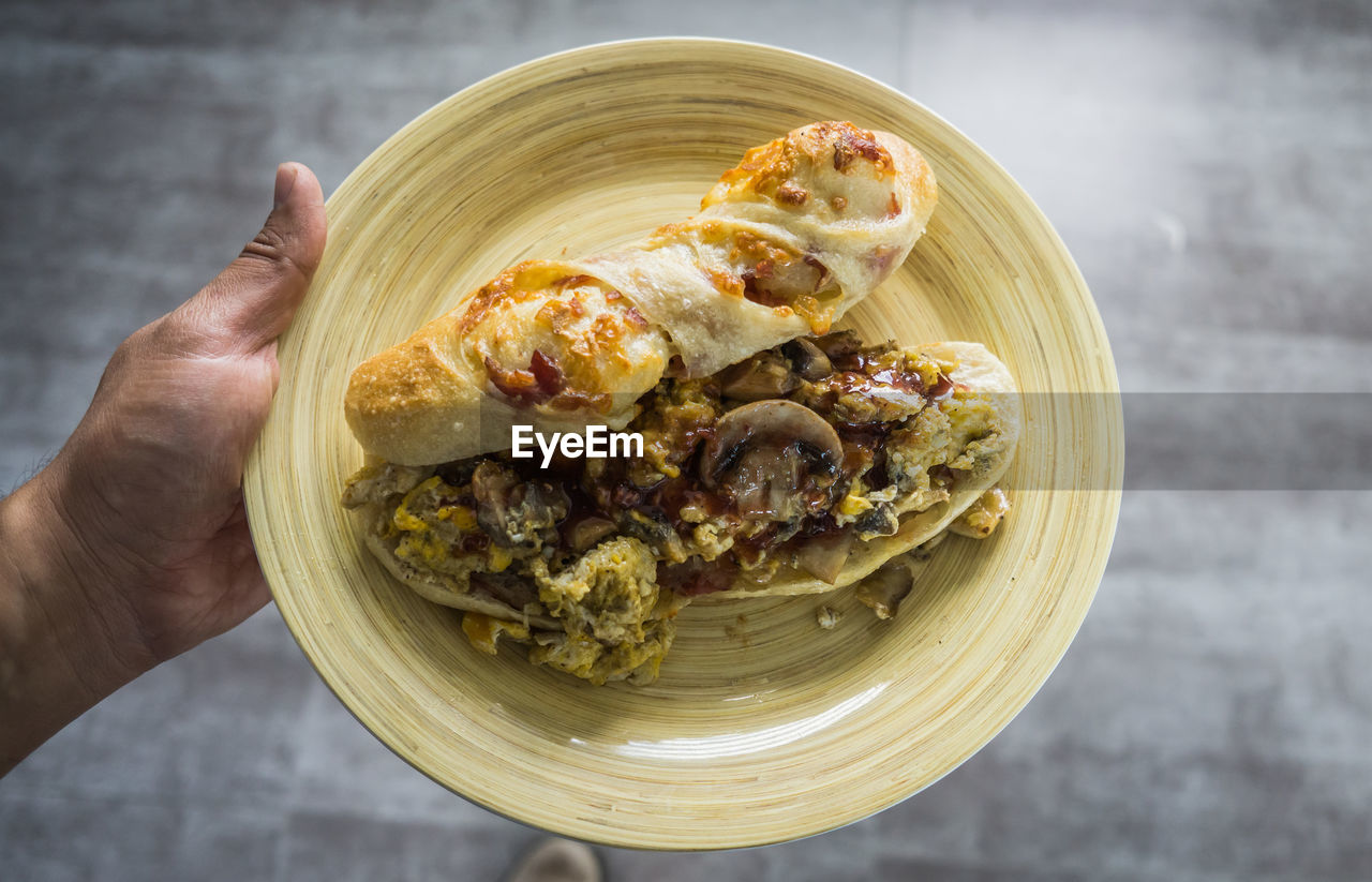 Close-up of hand holding sandwich on plate