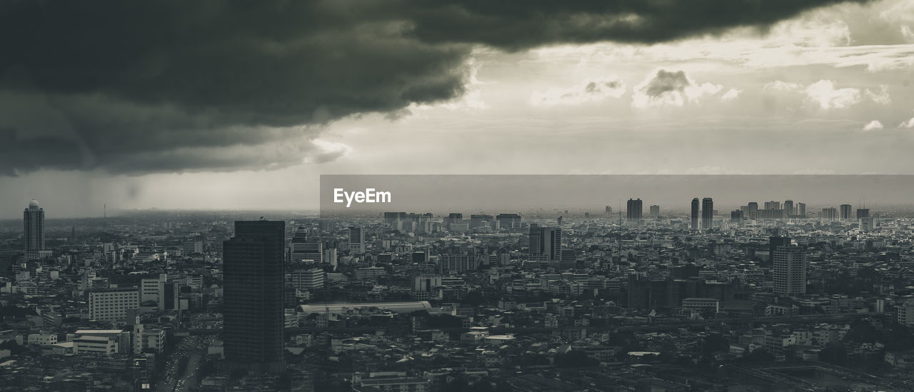 Aerial view of cityscape against cloudy sky