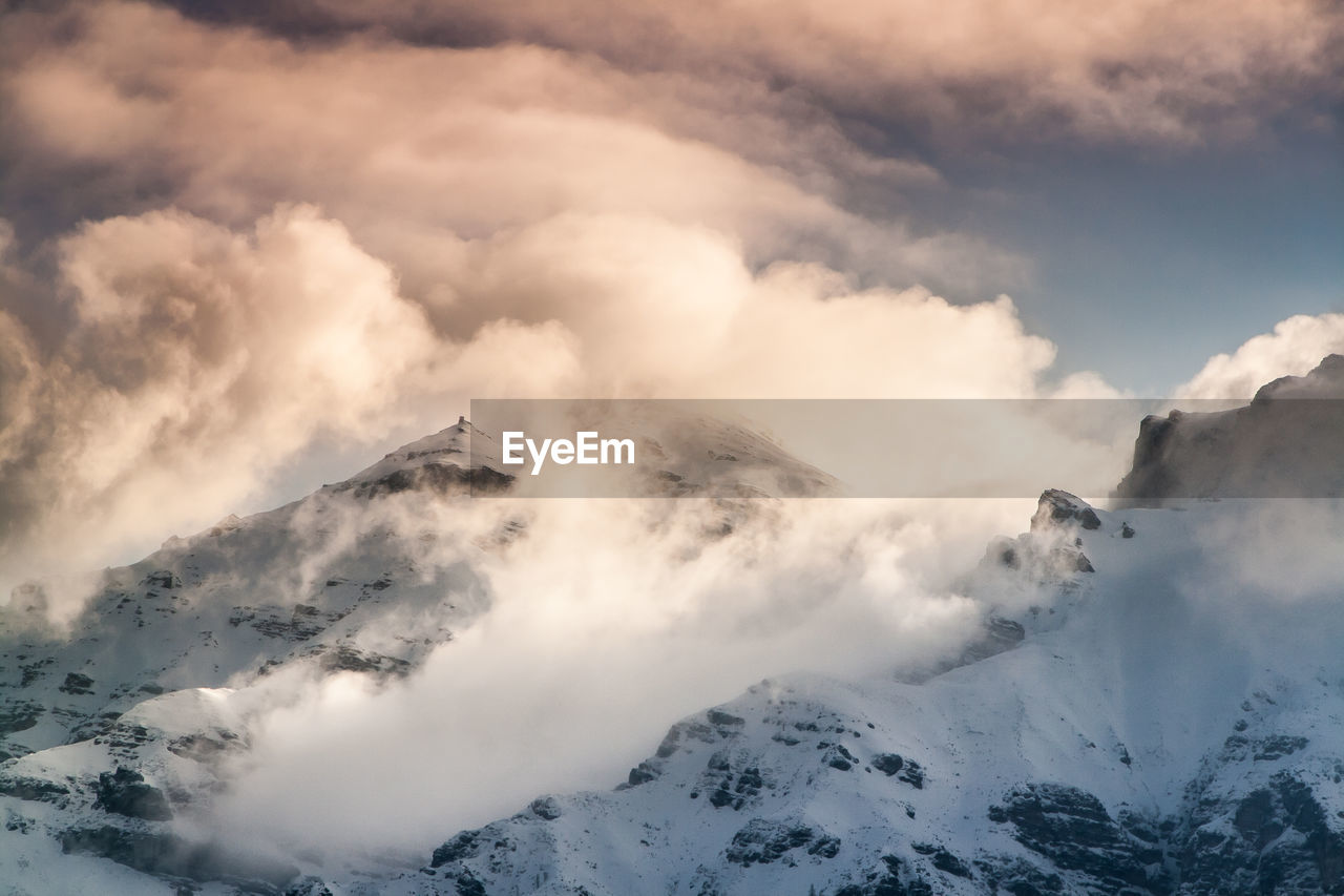 Scenic view of snowcapped mountains against cloudy sky