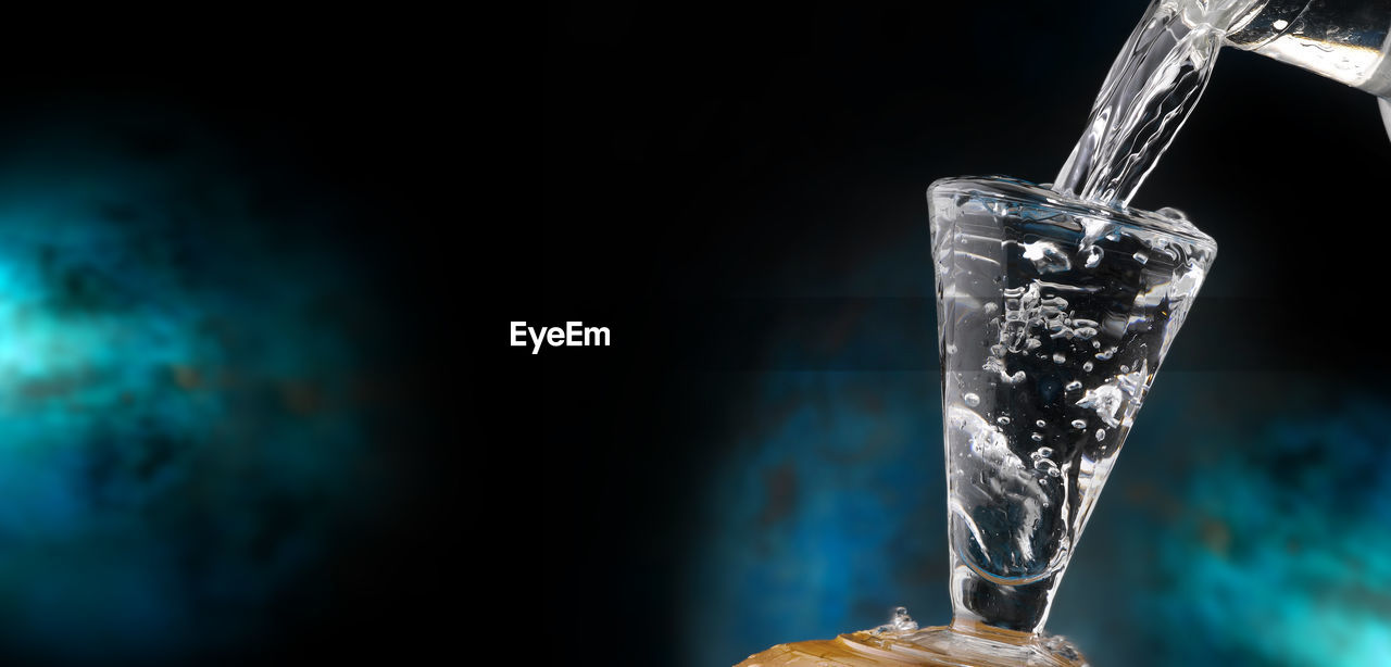 CLOSE-UP OF ICE CUBES IN GLASS AGAINST WATER