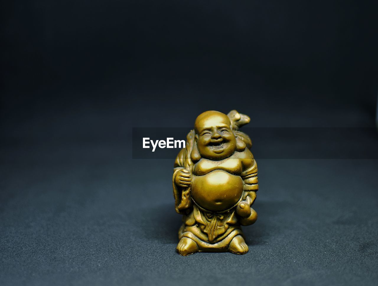 Close-up of buddha statue on table against black background