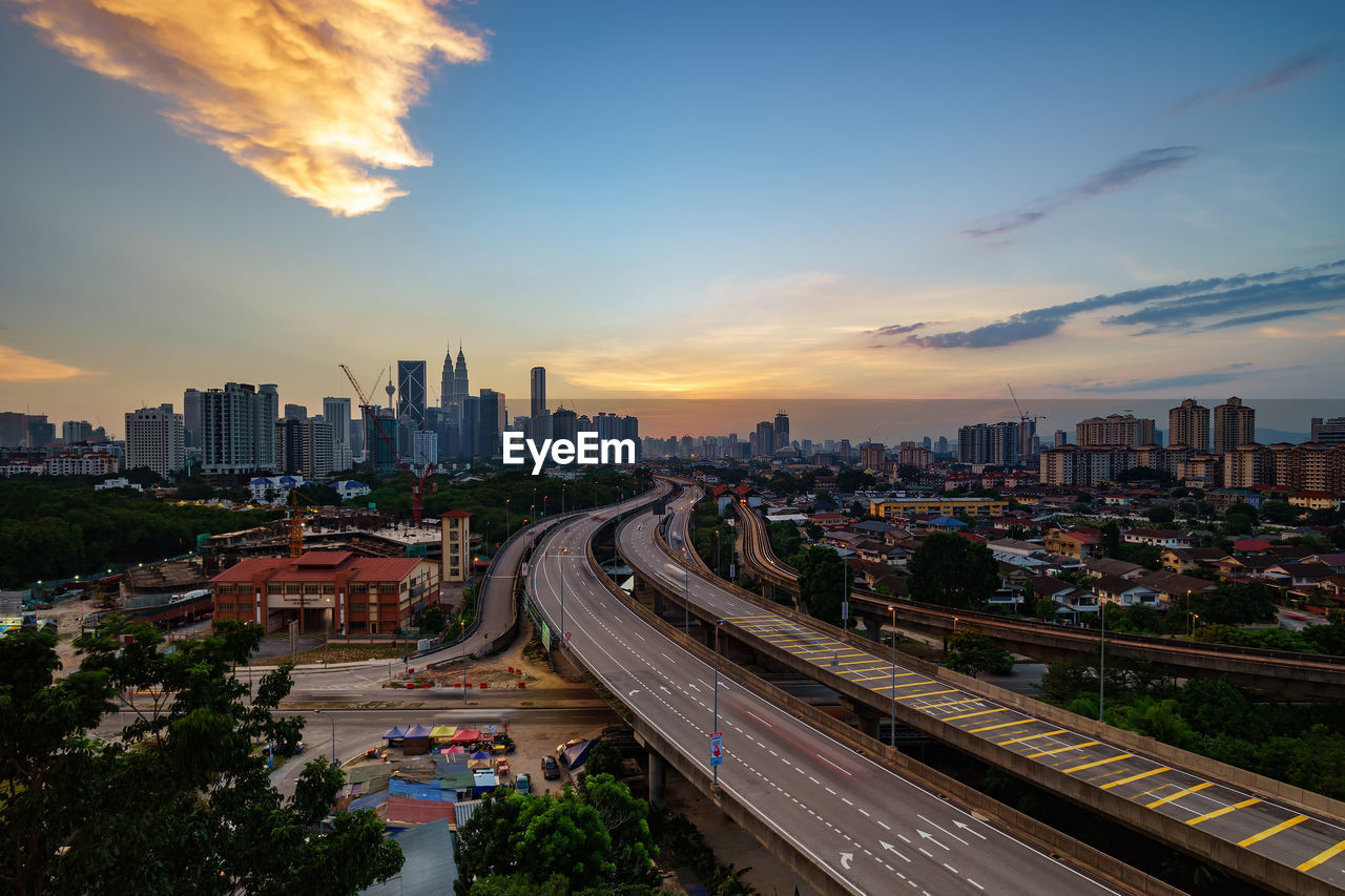 Distant view of petronas towers against sky during sunset in city