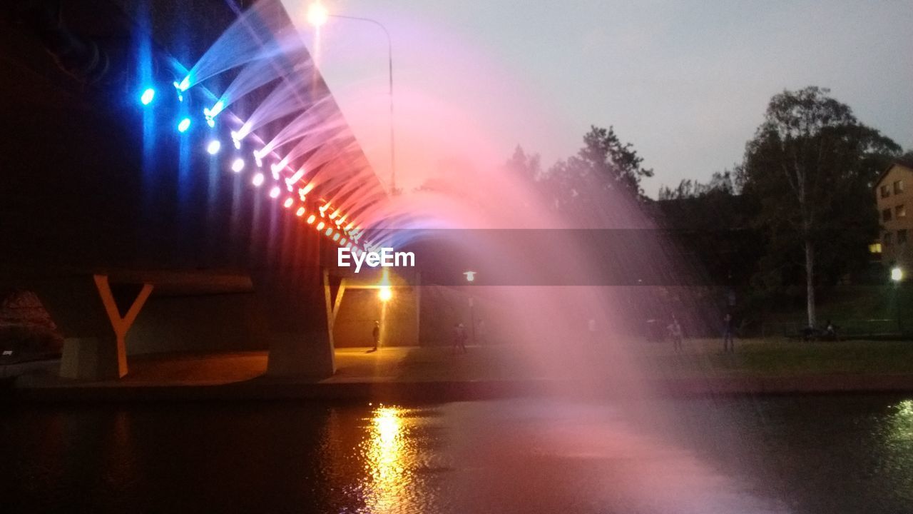 ILLUMINATED LIGHT TRAILS ON ROAD ALONG STREET AT NIGHT