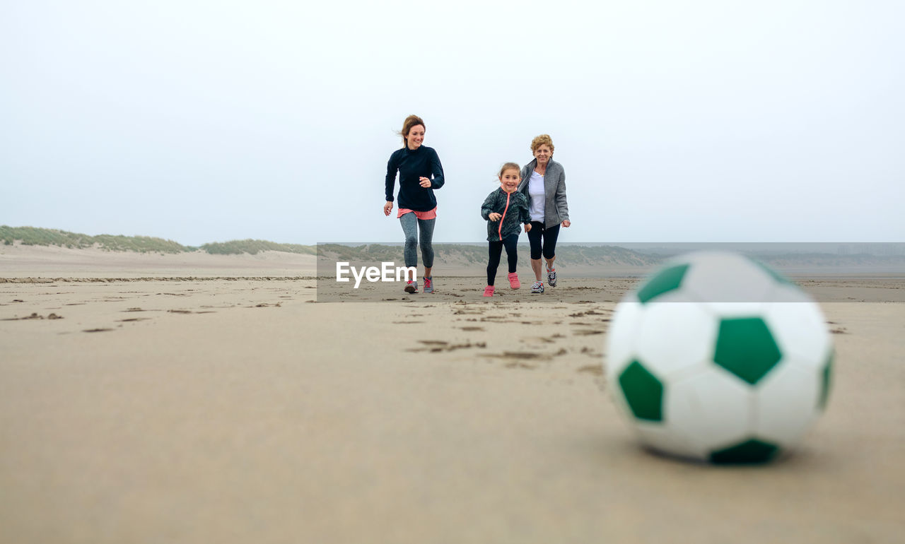 Happy family playing with ball at beach