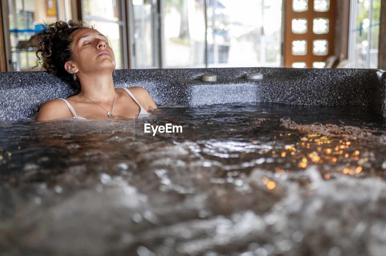 Mixed race woman relaxing in a hot tub during a spa day.