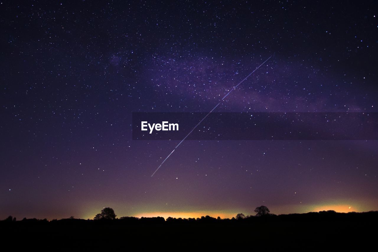 Low angle view of silhouette landscape against star field at night