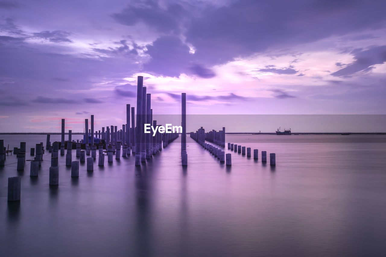 Wooden posts on pier over sea against sky