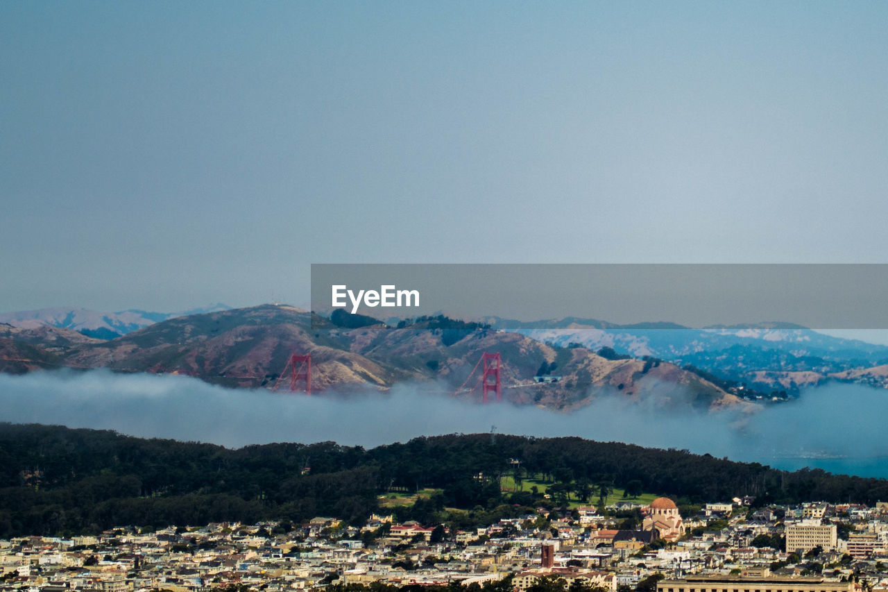 Aerial view of townscape by mountains against clear sky