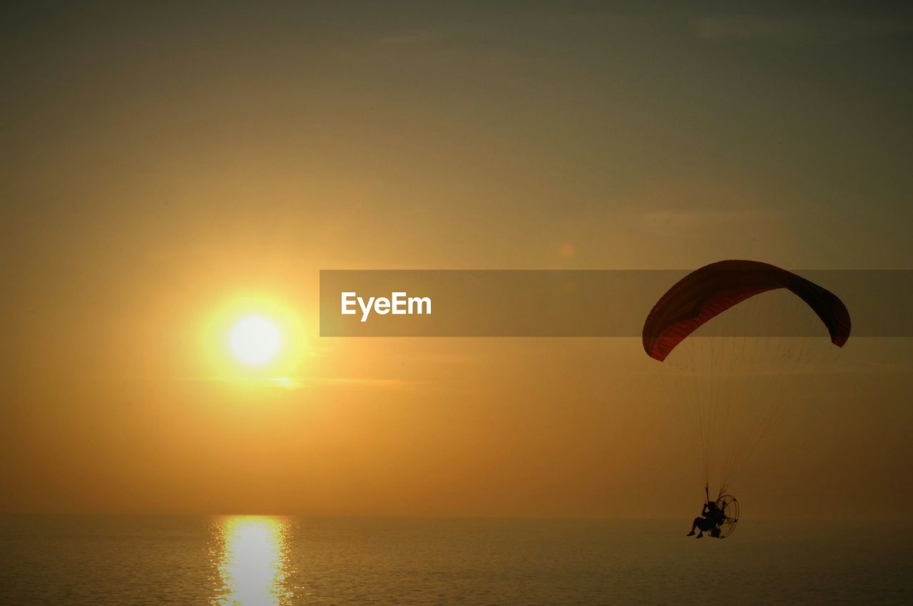Paragliding over lake michigan against sky during sunset