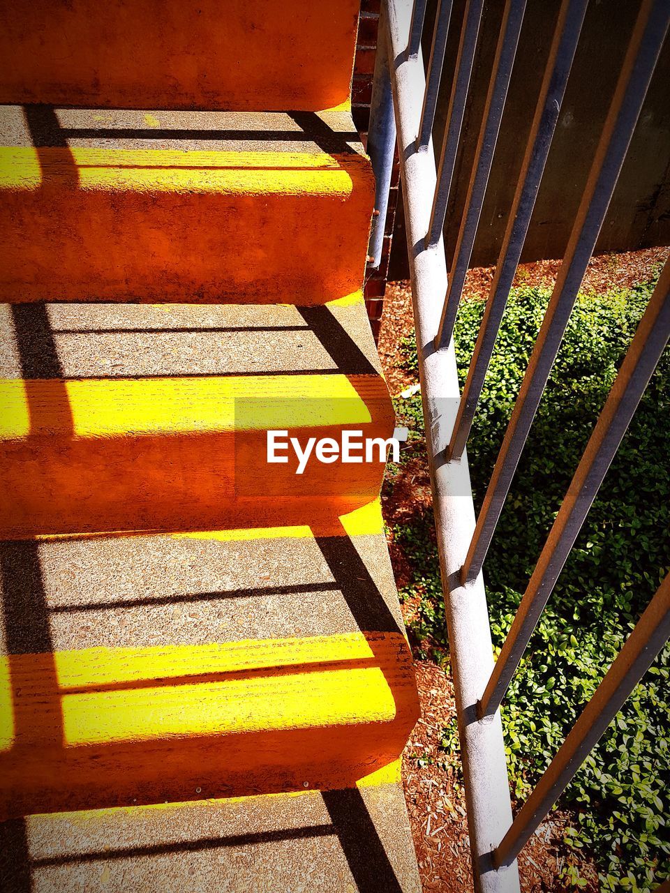 HIGH ANGLE VIEW OF EMPTY BENCH AGAINST YELLOW WALL