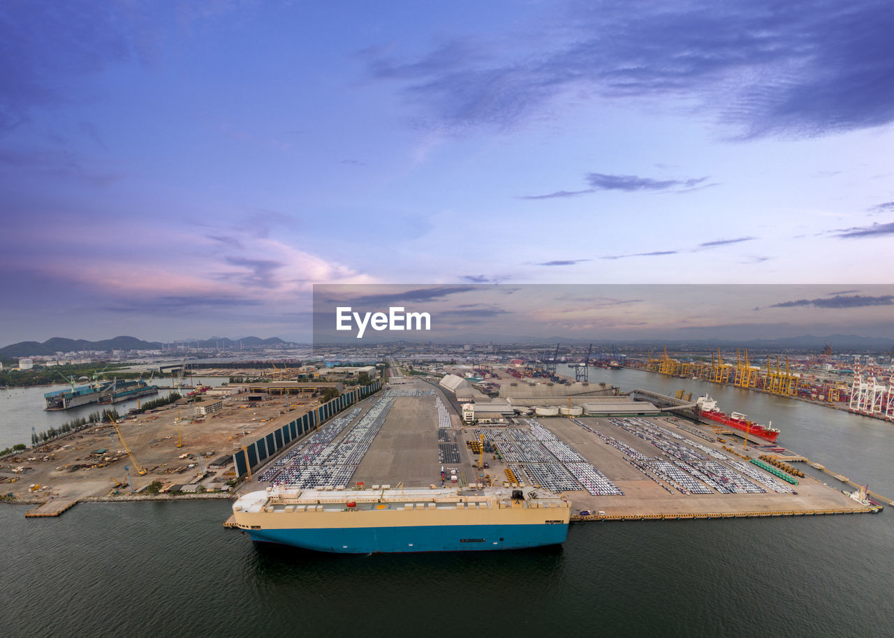 Aerial logistics commercial vehicles waiting to be load on to a car carrier ship at dockyard