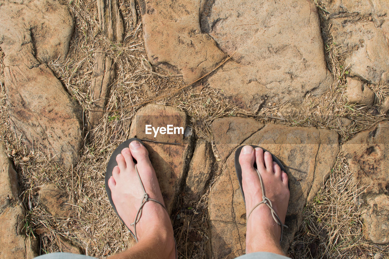 Feet in minimal sandals on stony path