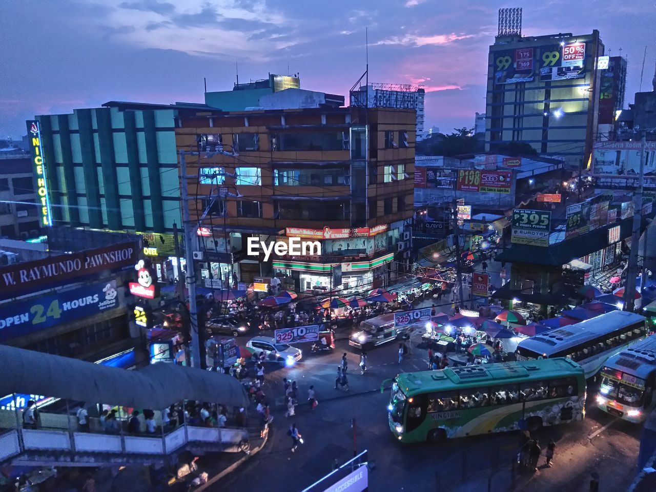 High angle view of vehicles and crowd on street by buildings at dusk in city
